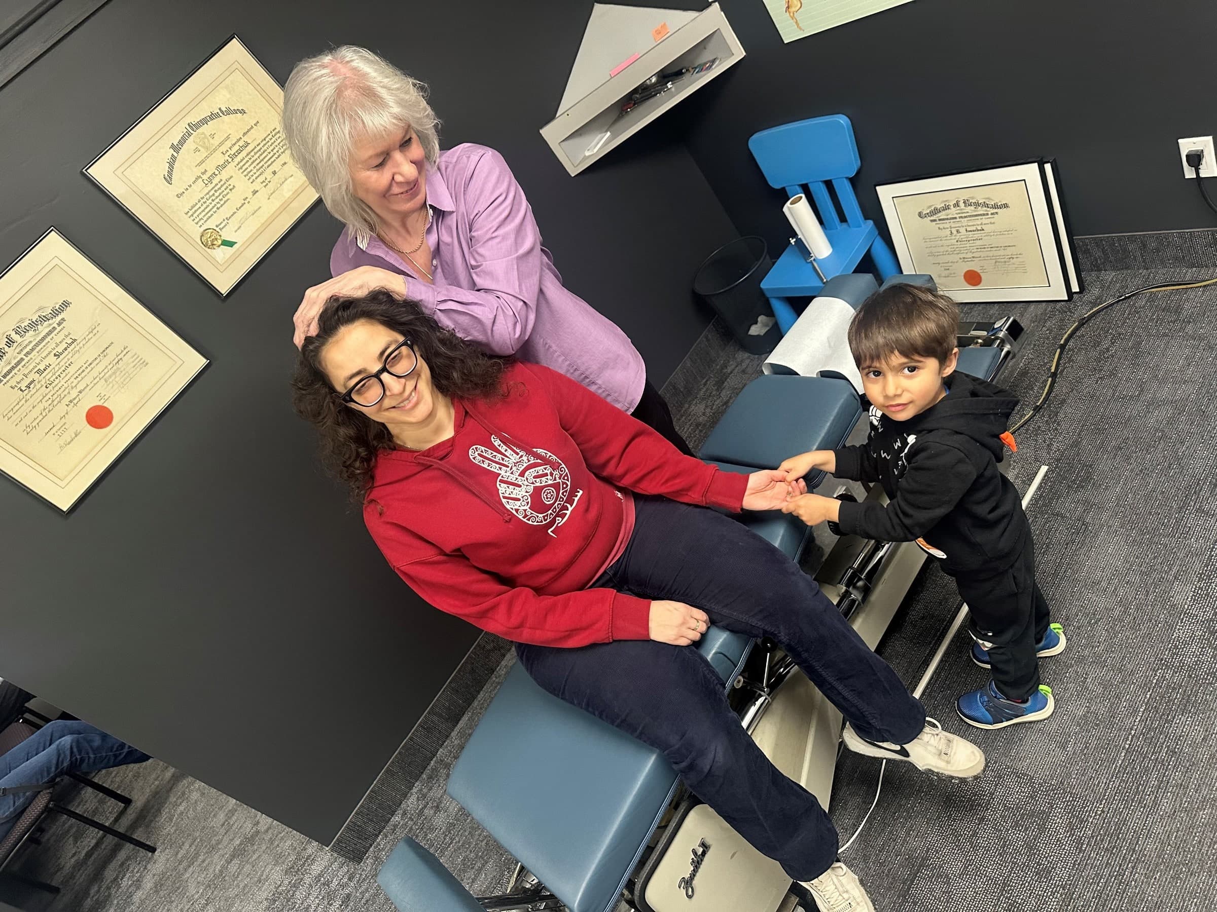 Dr. Lynne, chiropractor at Life Chiropractic Centre in Burlington, Ontario, supervising a young patient using an exercise bike.