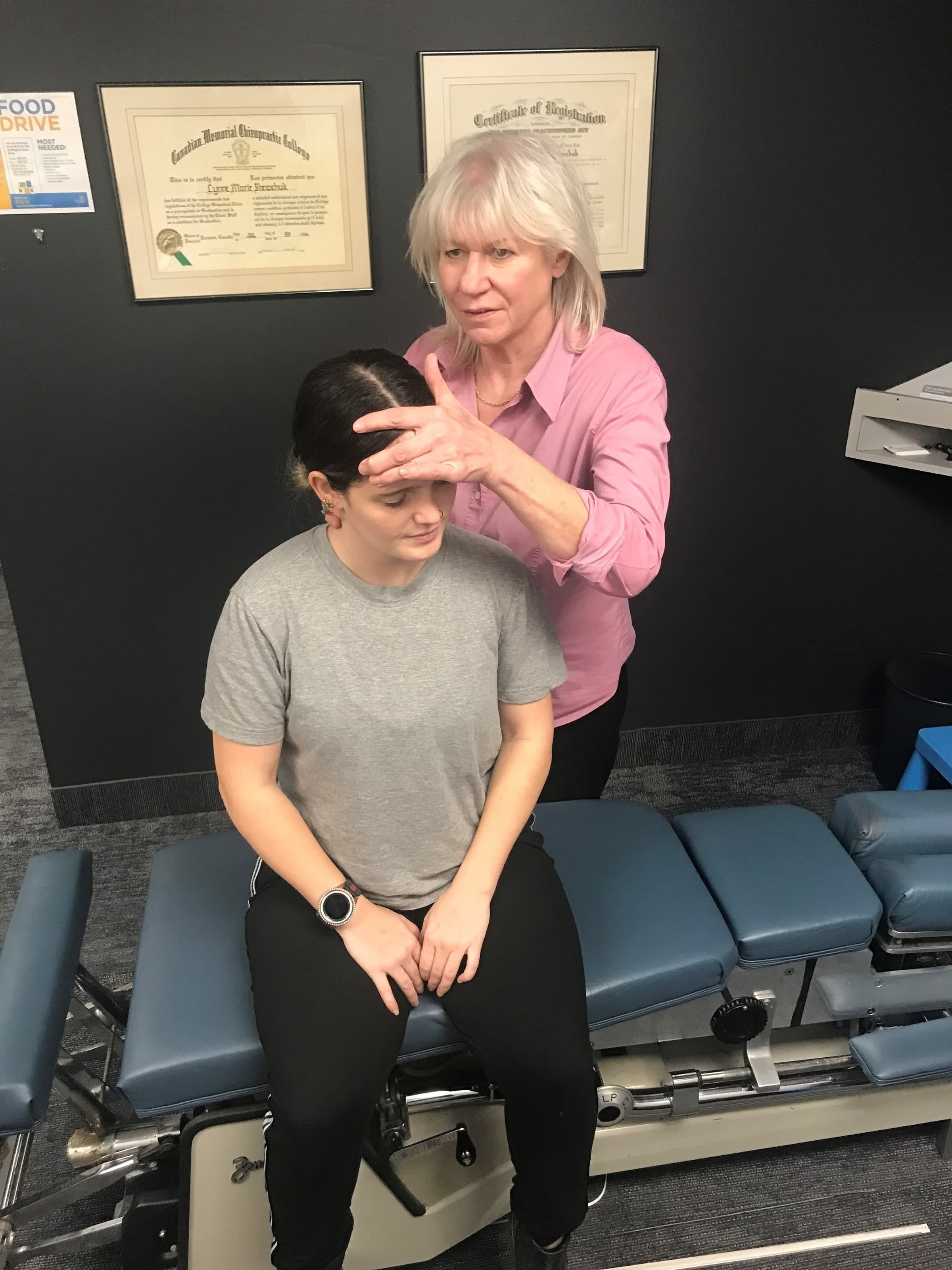 Dr. Lynne, chiropractor at Life Chiropractic Centre in Burlington, Ontario, performing a head and neck examination on a seated patient