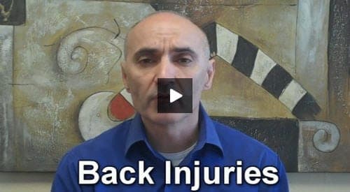 A male healthcare professional in a blue shirt discusses back injuries while seated in front of an abstract medical illustration